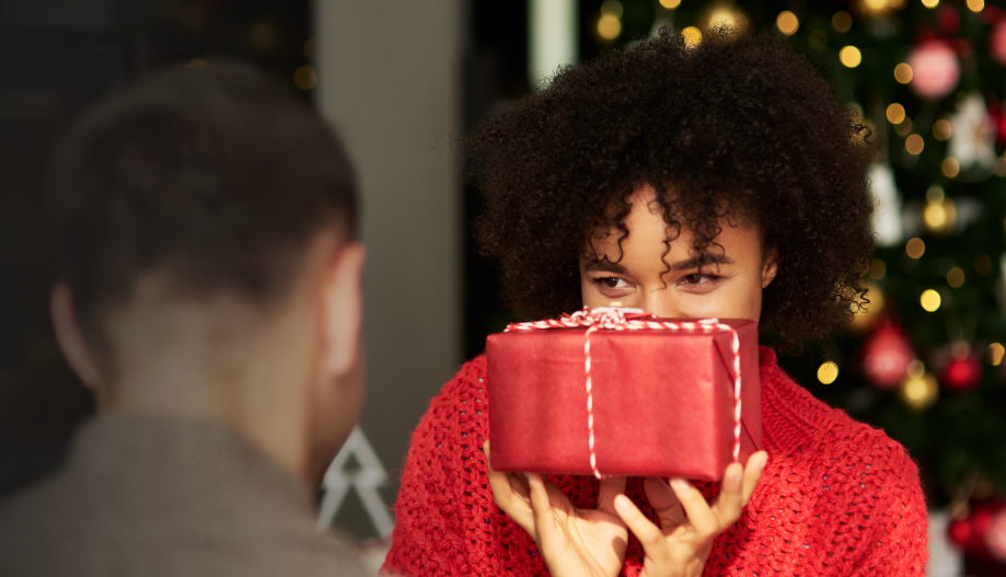 A woman holds a present wrapped in red wrapping paper